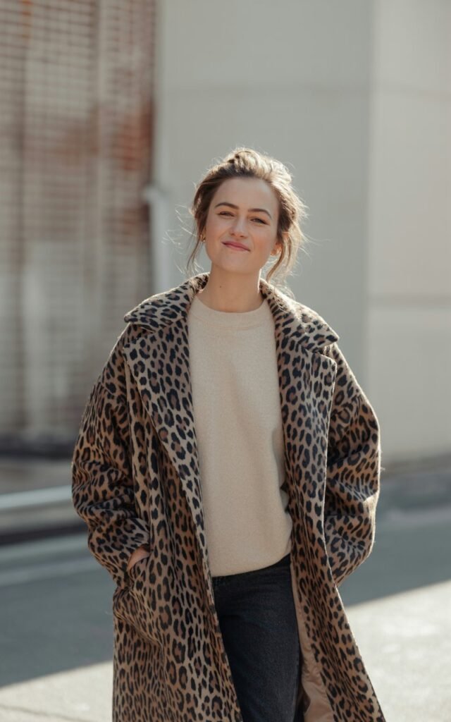 A natural-looking young woman wearing a bold statement coat over neutral basics. Theme quirky fashion