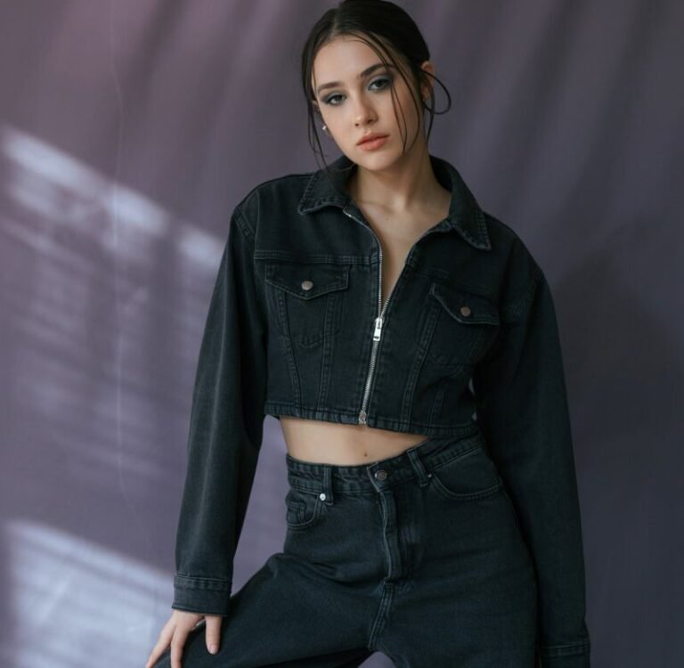 A natural-looking young woman wearing a cropped jacket paired with wide-leg black jeans. Theme emo outfits