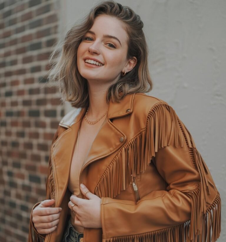 A natural-looking young woman wearing a fringed or tassel jacket. Theme quirky fashion