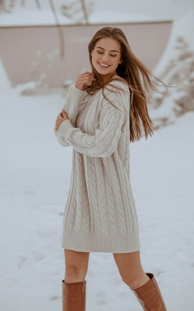 A natural-looking young woman wearing a knit dress with knee-high boots. Theme winter fashion outfits