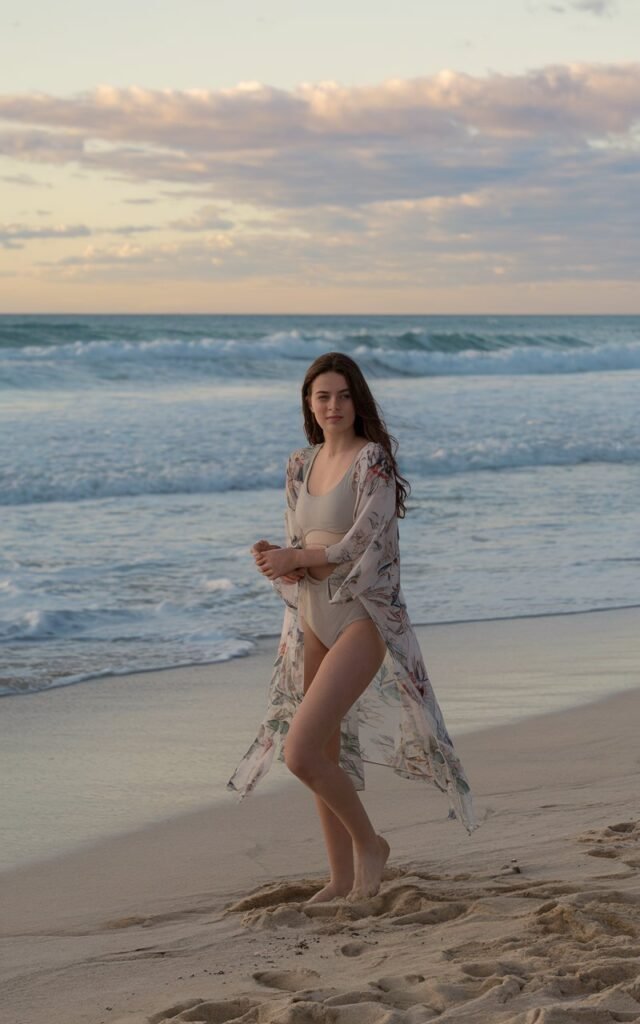 A natural-looking young woman wearing a lightweight kimono over swimwear. Theme beach outfits