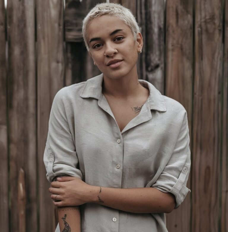 A natural-looking young woman wearing a simple button-down shirt with sleeves rolled up and relaxed-fit pants. Theme tomboy outfits