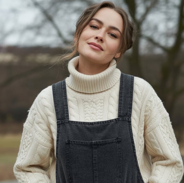 A natural-looking young woman wearing a turtleneck sweater with overalls. Theme winter fashion outfits