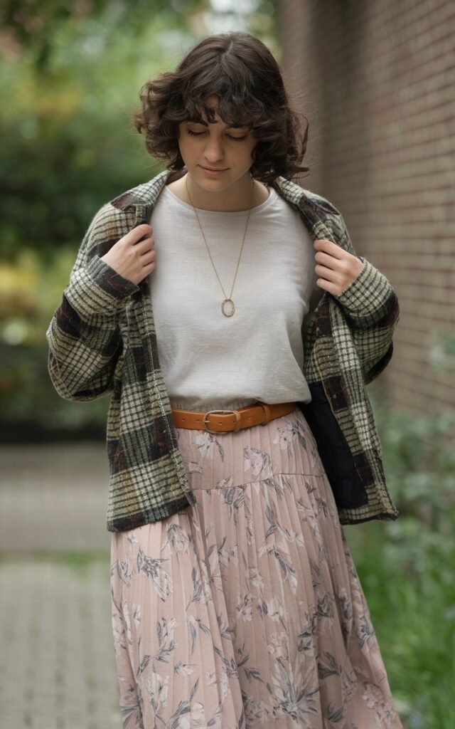 A natural-looking young woman wearing a feminine skirt contrasted with a slightly boxy tee. Theme stylish outfits