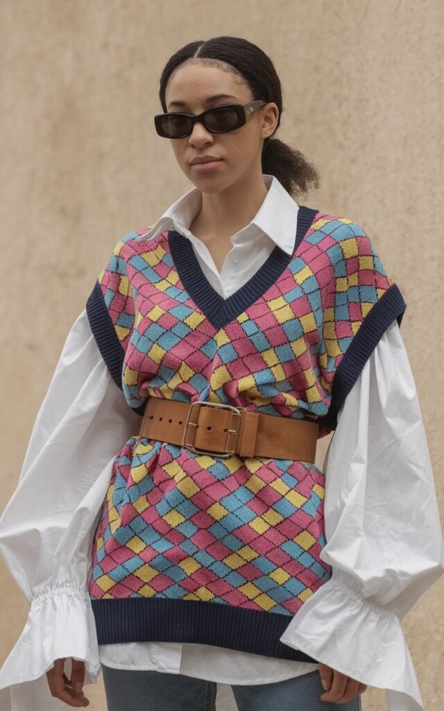 A natural-looking young woman wearing a wide belt cinched over her outfit. Theme 80s outfits