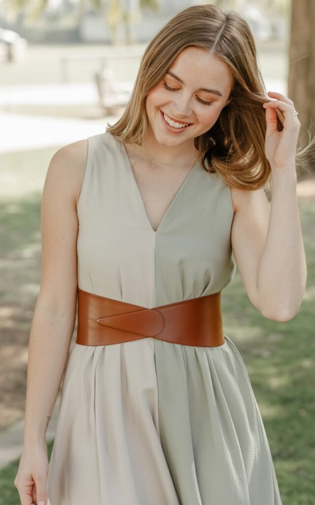 A natural-looking young woman wearing a simple dress elevated with a bold statement belt. Theme family photo outfits