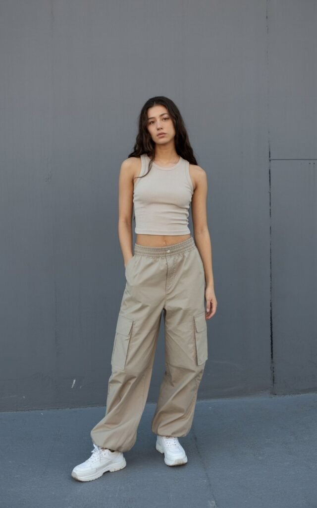 A natural-looking young woman wearing baggy cargo pants styled with a ribbed tank top. Theme 90s outfits