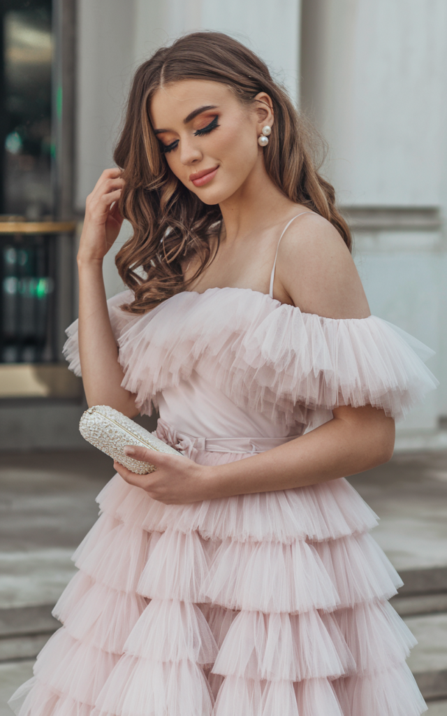 A natural-looking young beautiful woman wearing a dreamy white tulle dress with soft layered fabric, delicate heels, pearl earrings, and a small clutch, styled with romantic curls for a princess-inspired graduation outfit